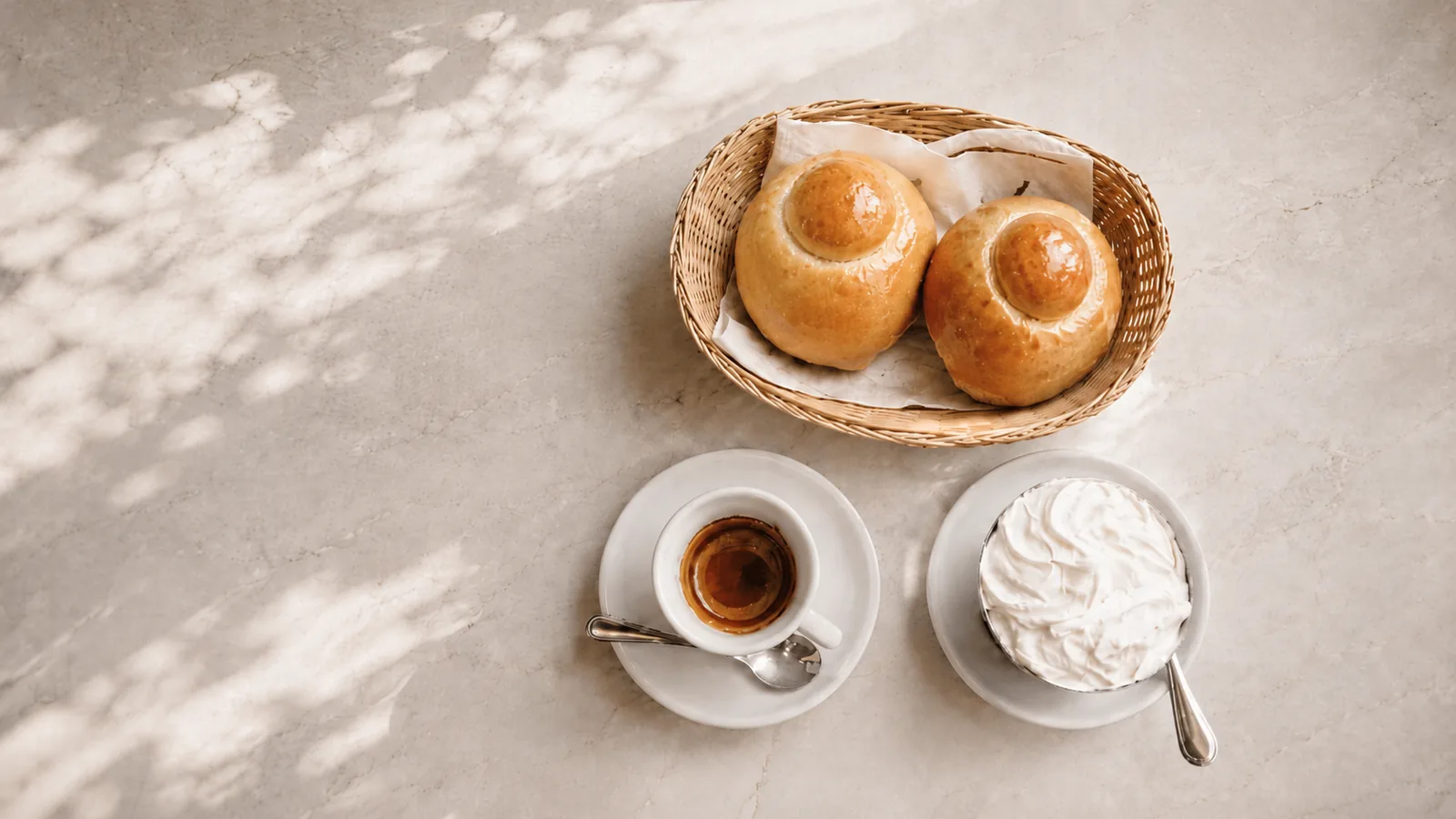 Colazione siciliana sul marmo: brioche col tuppo, espresso e panna